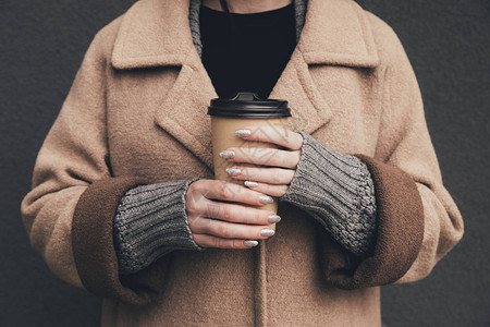 穿着外套的女人拿着一次咖啡的剪影图片