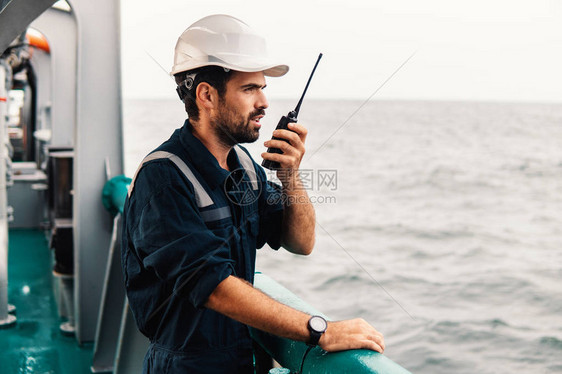 船舶或船舶甲板上的海事甲板高级船员或大副他手里拿着甚高频对讲图片