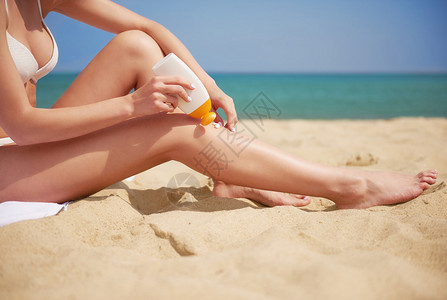 女人在沙滩上施晒霜严图片