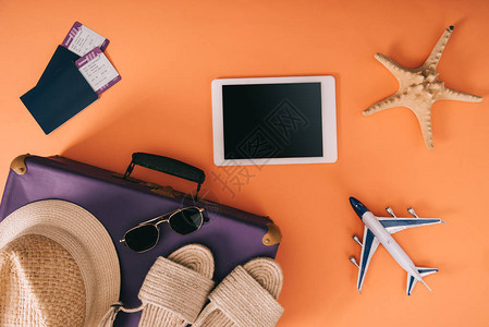 旅行袋飞机模型数字平板电脑和带有橙色背景机票的护照上夏季附件图片