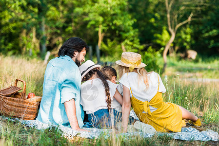 父母和儿童在野餐时坐在毯子图片
