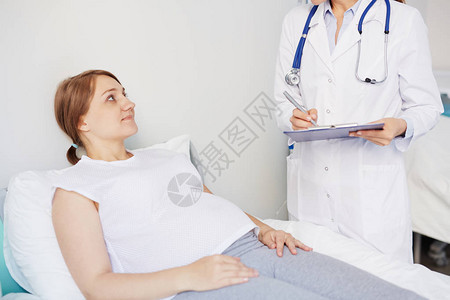 年轻怀孕病人躺在医院床上背景图片
