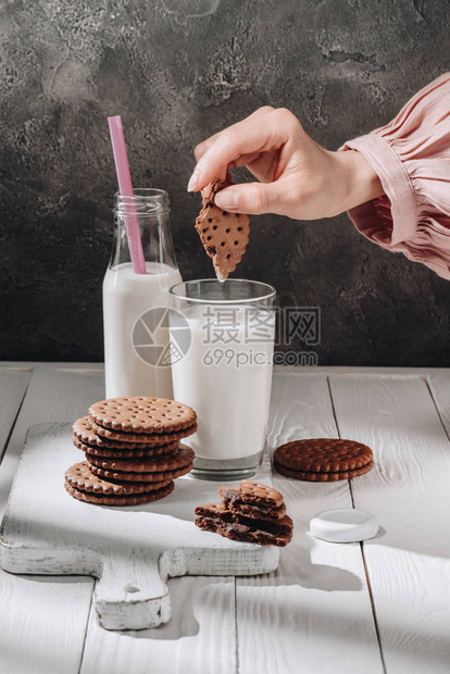 妇女将巧克力饼干浸入牛奶杯图片
