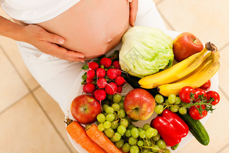 孕妇腿上放着一碗水果和蔬菜图片