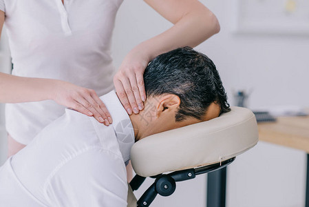 颈部,为商人做颈部按摩的按摩师近身拍背景