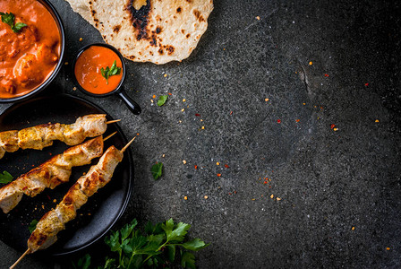 印度菜传统菜辣鸡tikkamasala黄油咖喱鸡印度烤饼黄油面包香料香草盛在碗里酱汁图片