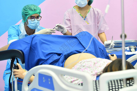 向躺在医院产房的床上的病人提供亚洲男妇产科和护士图片