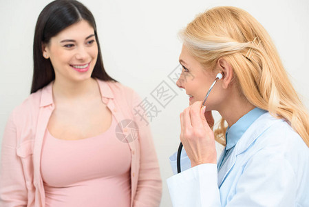 妇产科医生用听诊器听孕妇胎儿心跳的特写镜头图片