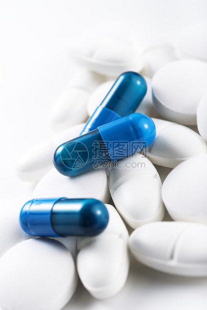 白色背景上的蓝色药丸和白色药片图片