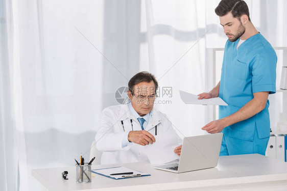 医生阅读文件并将其交给护士图片