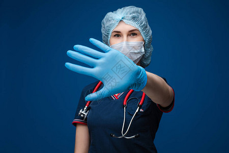 戴帽子面罩和手套在照相机上显示站牌的专业护士或医生图片