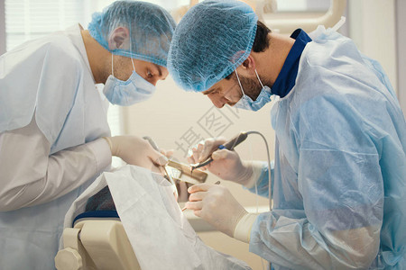 口腔科手术期间的牙科医生和助图片