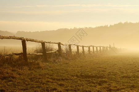 日出在雾蒙的田野上前景是木栅栏图片