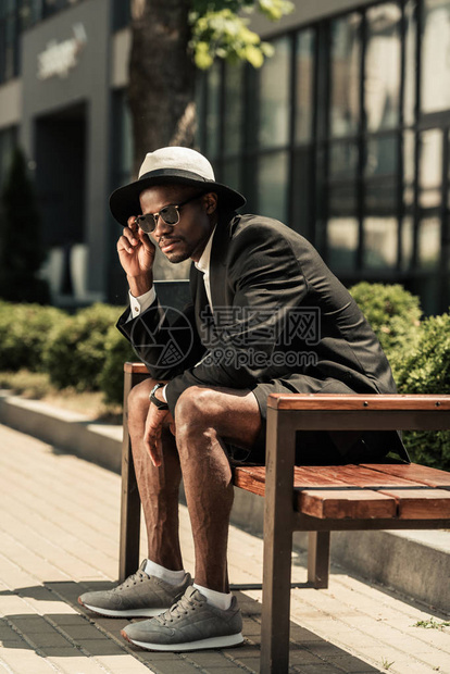 身戴Fedora帽子坐在长椅上的时髦的非图片
