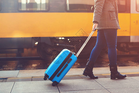 走在火车站的旅游妇女坐火车旅行拖着蓝色行李箱的女孩旅程概念生活方式图片