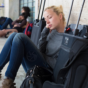 疲倦的女旅行者等待离开带着所有行李在车图片