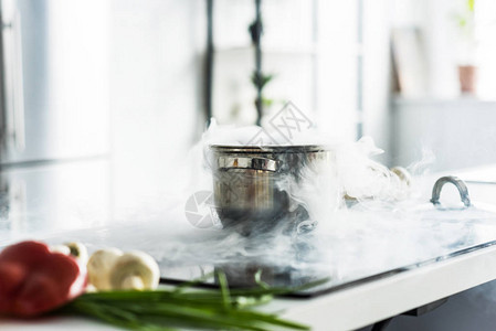厨房电炉上有蒸汽的平底锅图片