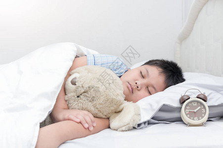 胖男孩睡觉在床上泰迪熊图片