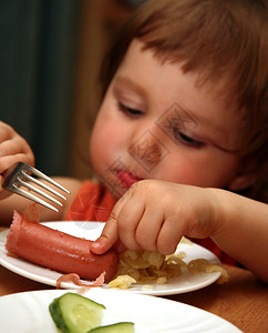 小孩吃香肠和通心粉在锋利的地带图片