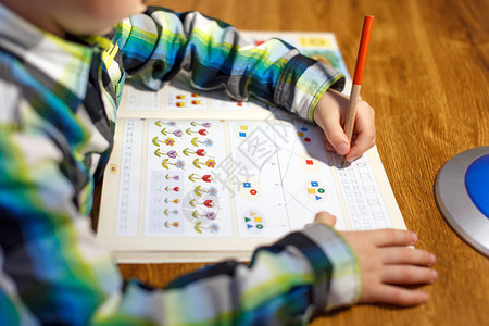 小男孩在家里做家庭作业用铅笔写进图片