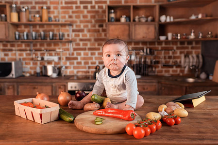 小男孩厨房桌上坐着各种生蔬菜图片