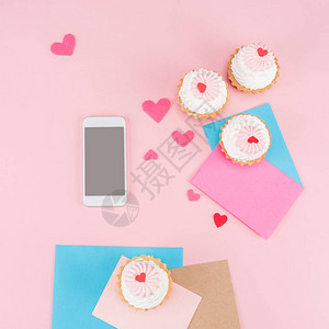 最美味的纸杯蛋糕带空白屏幕的智能手机和粉红色的心脏符号背景图片