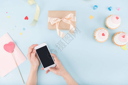 人手举起智能手机带蛋糕和礼物盒的喜悦背景图片