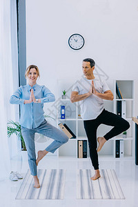 适合女商人和她的教练在办公室以树式练习瑜伽图片