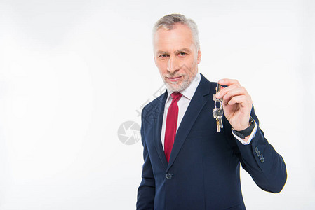 笑成熟的商人拿着钥匙看着在白色上被图片