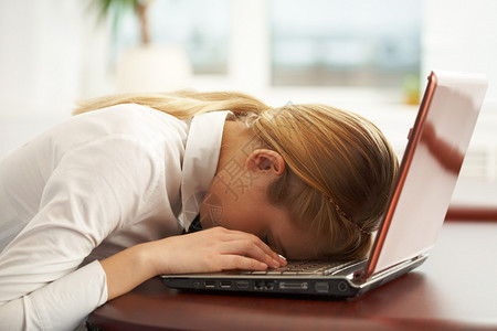 在笔记本电脑键盘上露面的非常疲劳的女商图片