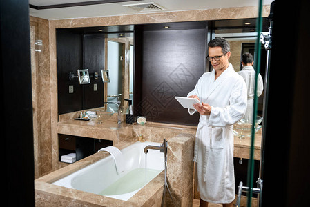 穿着浴袍的商人在旅馆浴室洗浴间图片