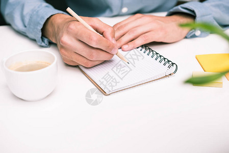 用咖啡杯写日记的男手的剪影图片
