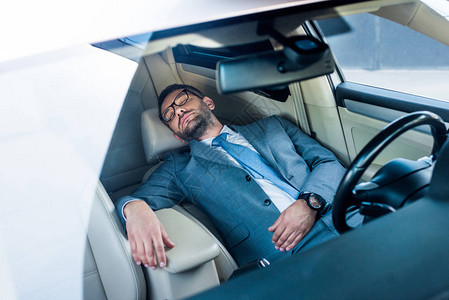戴着眼镜睡在车里的疲惫商人图片