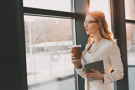 身着白色西装数字平板电脑和咖啡的有吸引力的女商人图片