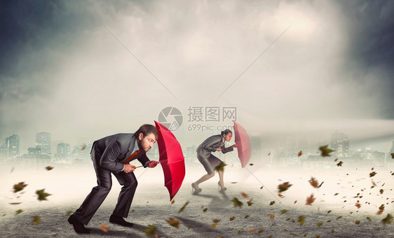 商人和女商人在暴风雨中保护自己免受带雨图片