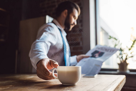 集中的商人早上在厨房看报纸喝咖啡时在图片