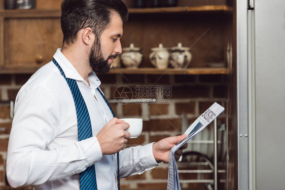 商人早上在厨房看报纸和喝咖啡图片
