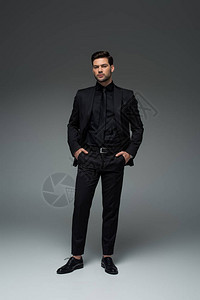 穿时装的黑西装的男人站在灰色的口袋图片