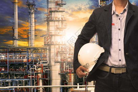 戴安全帽的工程师站在重石化行业炼油厂建筑结构前图片