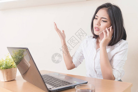 在办公室的办公桌里用智能电话穿着西装在线上工作的冒牌女商图片