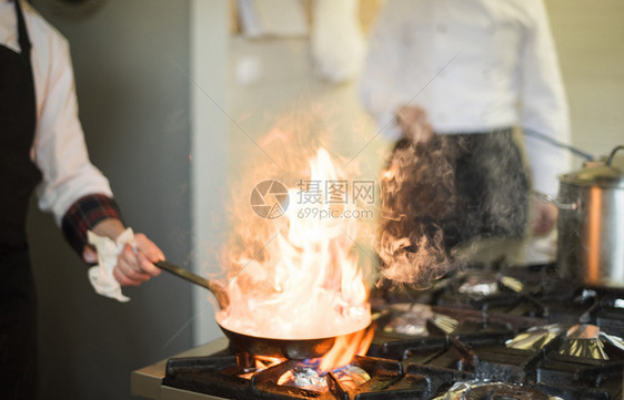 商用厨房着火的厨师煎锅图片