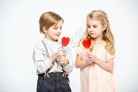 可爱的小男孩与女孩抱着心脏形状的棒糖图片
