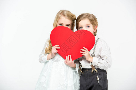 两个可爱的孩子躲在红色纸心的背后图片