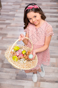 小姑娘拿着满篮子的彩色复活节鸡蛋背景图片