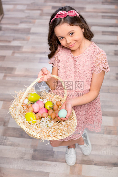 小姑娘拿着满篮子的彩色复活节鸡蛋图片