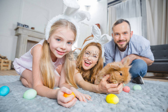 家庭在家里躺在地毯上玩蛋和复活节鸡图片