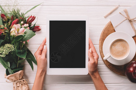 女在表面用一块花束和一杯咖啡包着的花束保持一片状平板图片