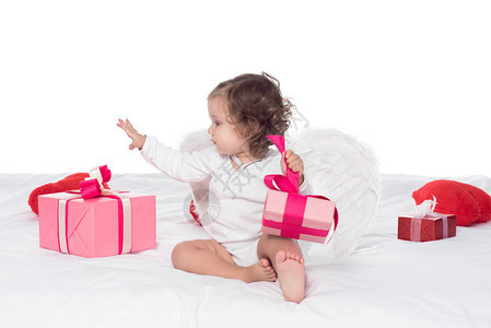 可爱的宝贝天使坐在床上带着礼物背景图片