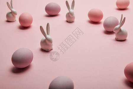 粉红色背景中的玩具兔子和彩绘复活节彩蛋背景图片