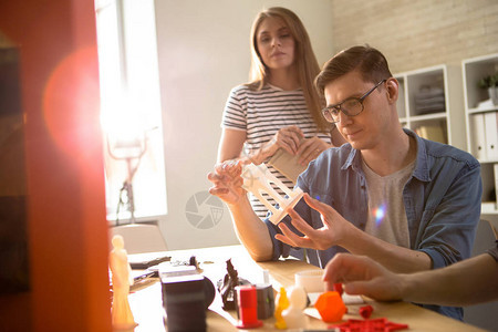 自信的年轻眼镜技术员在与现代实验室的同事开会时对3D打印细节图片